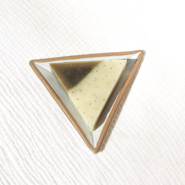 A triangle soap on a triangular soap dish against textured linen