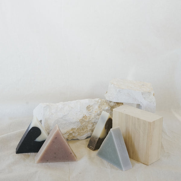 Four triangle soaps sitting among stone and wood