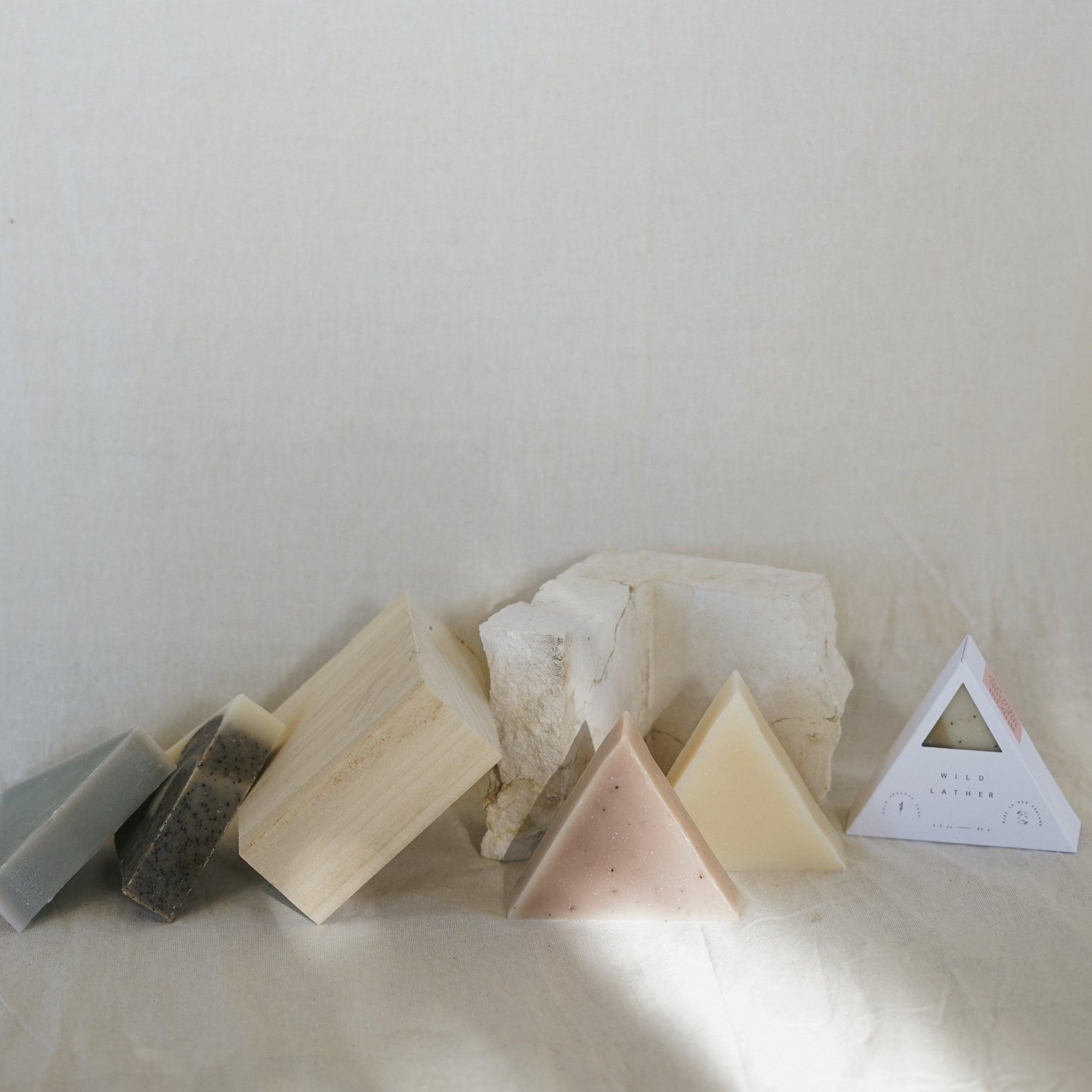 Five triangle soaps leaning against wood and stone
