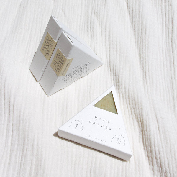 Three packaged triangle soaps against textured linen