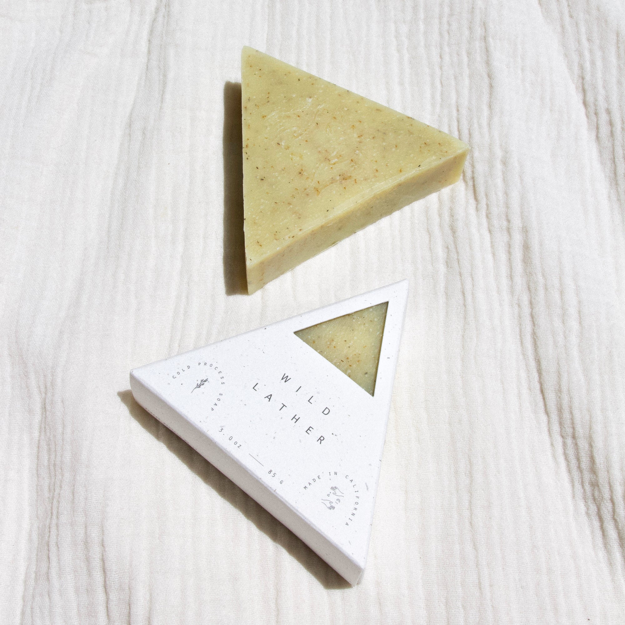 A packaged and unpackaged triangle soap next to one another