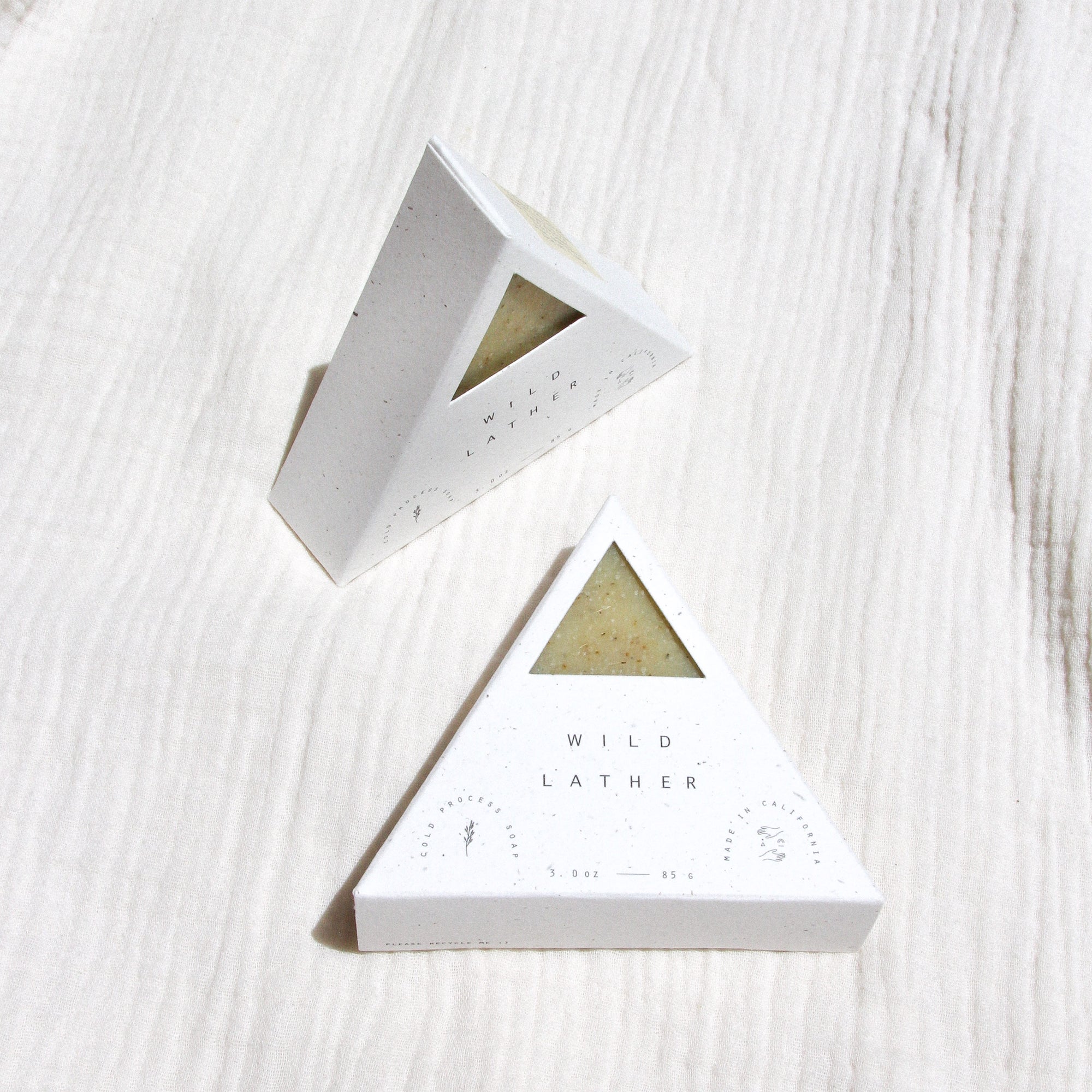 Two packaged triangle soaps against textured linen