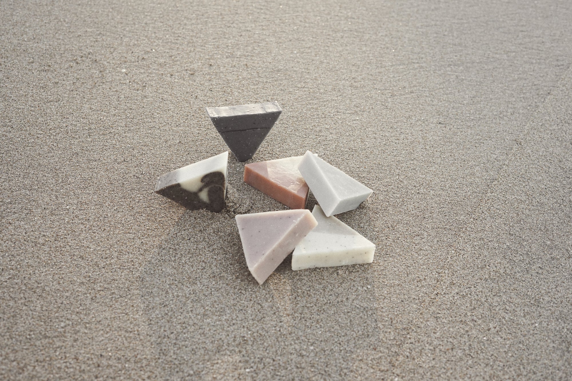 Six soap triangles on a sandy beach