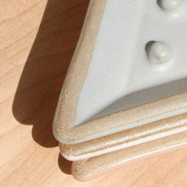 A closeup of three triangular ceramic soap dishes stacked on top of one another 