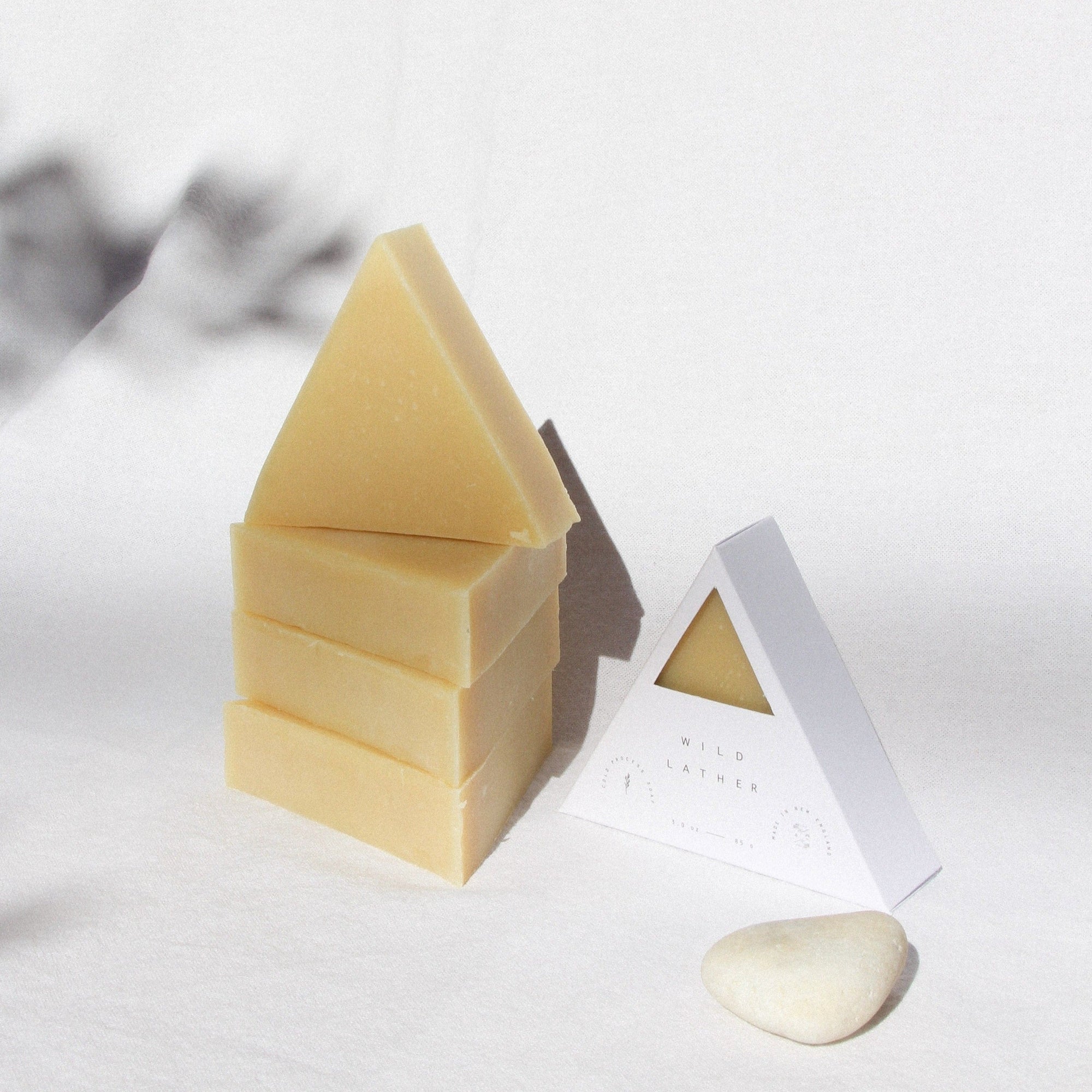 Golden triangle soaps stacked on top of one another against a white cloth in the sun
