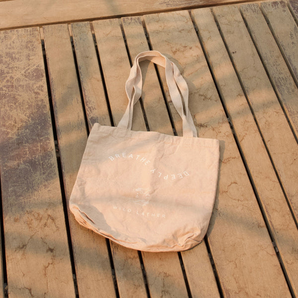 A pale blush tote against a wood deck