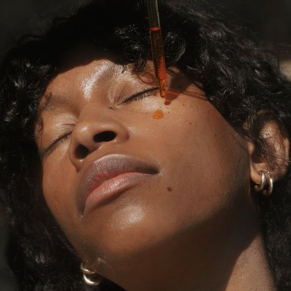 A woman dropping Sun Milk Oil onto her face