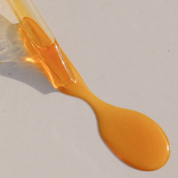 Golden Sun Milk Oil spilling out onto a beige surface