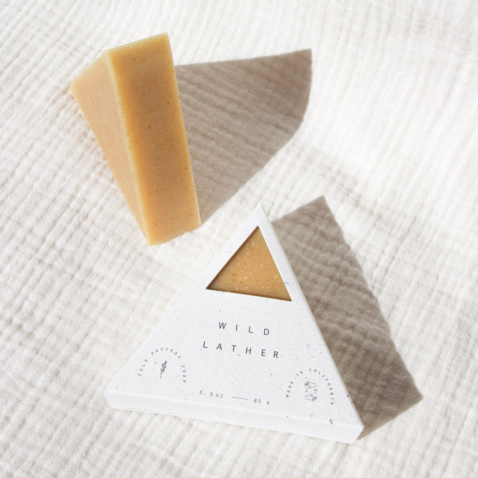Turmeric colored triangle soap packaged in a speckled white triangle box