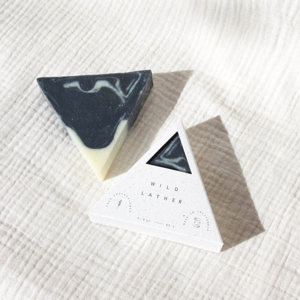 Activated charcoal triangle soap in speckled white triangle packaging against a textured white cloth