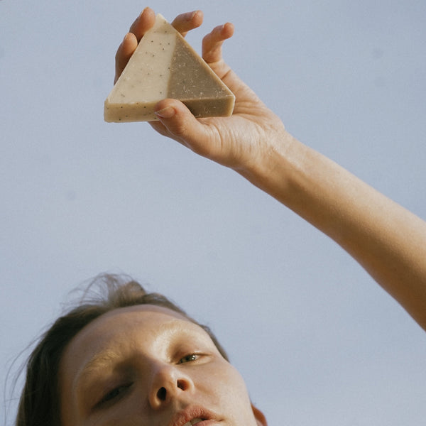 A woman holding an osaka soap triangle against the blue sky