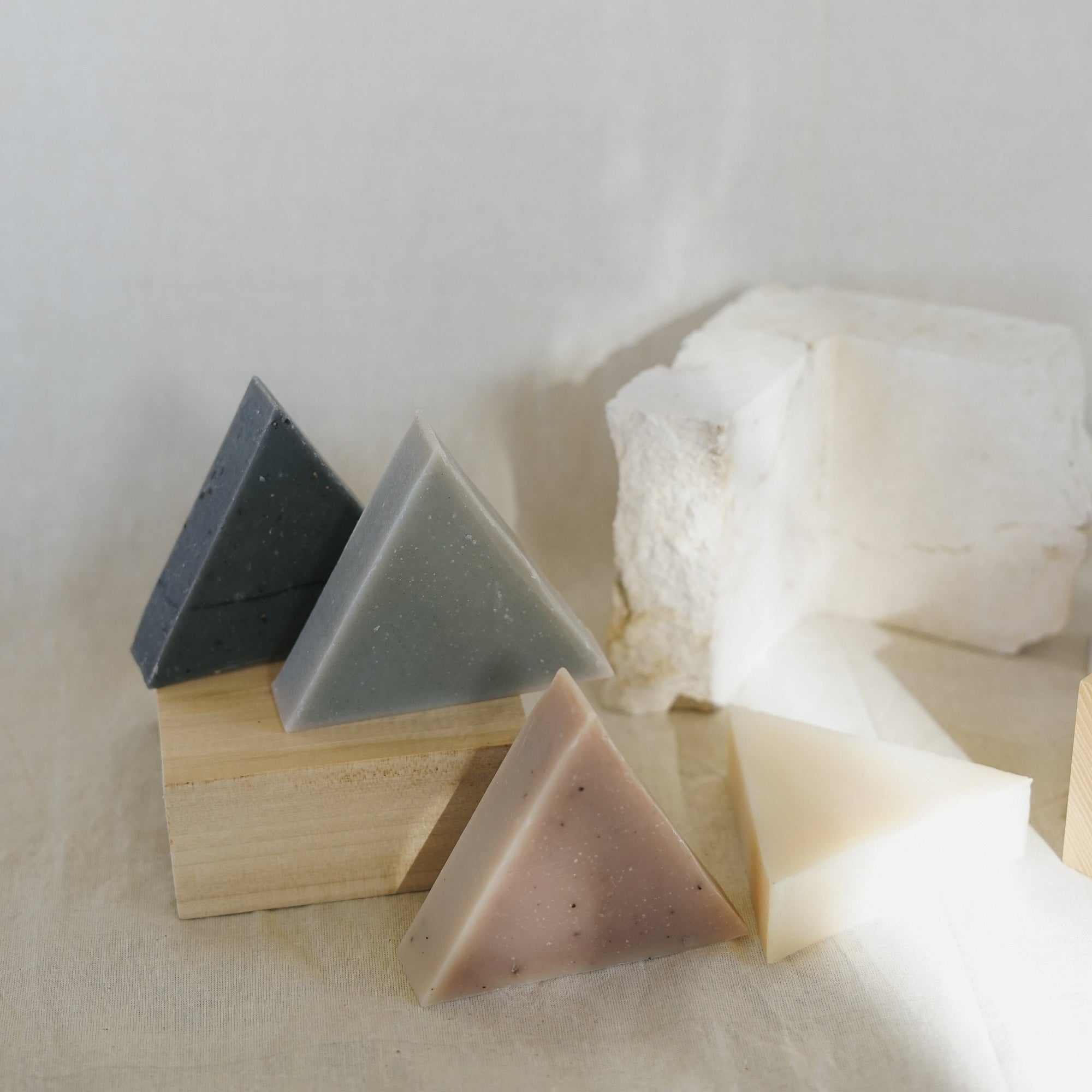 Four triangle soaps balancing on wood and stone