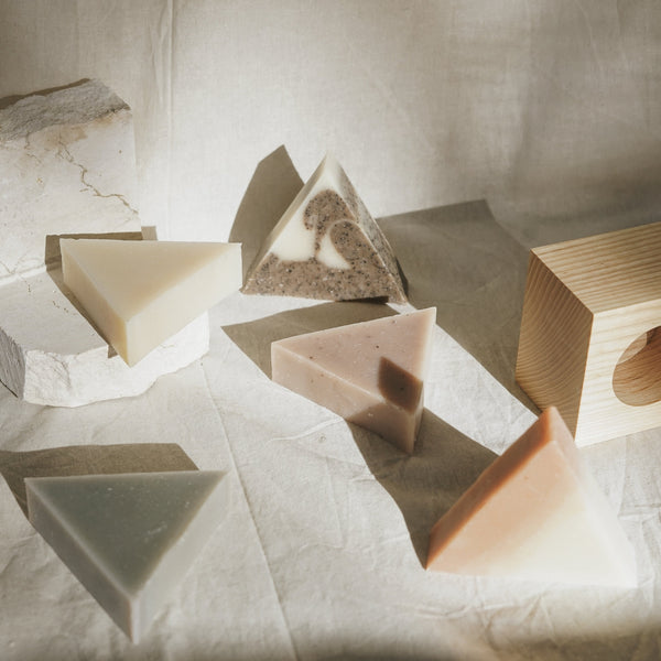 Five triangle soaps scattered among wood and stone 
