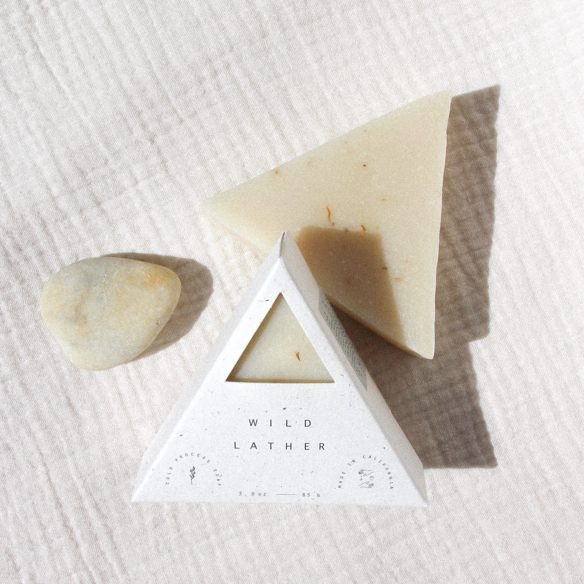 Two soaps and  a stone against textured beige linen